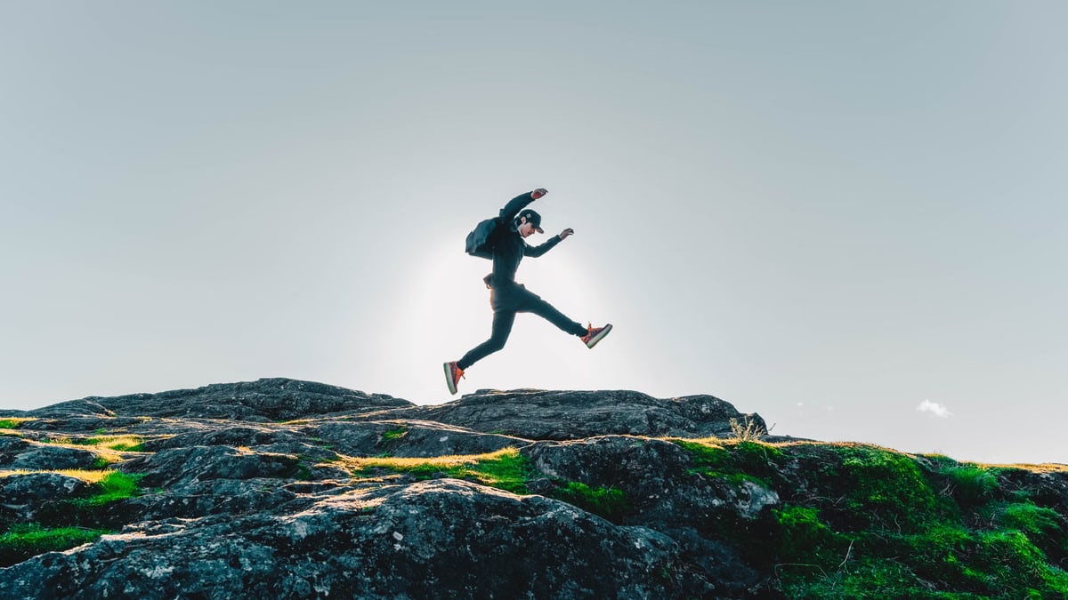 A person jumping over rocks with a clear sky background in British Columbia, Canada.